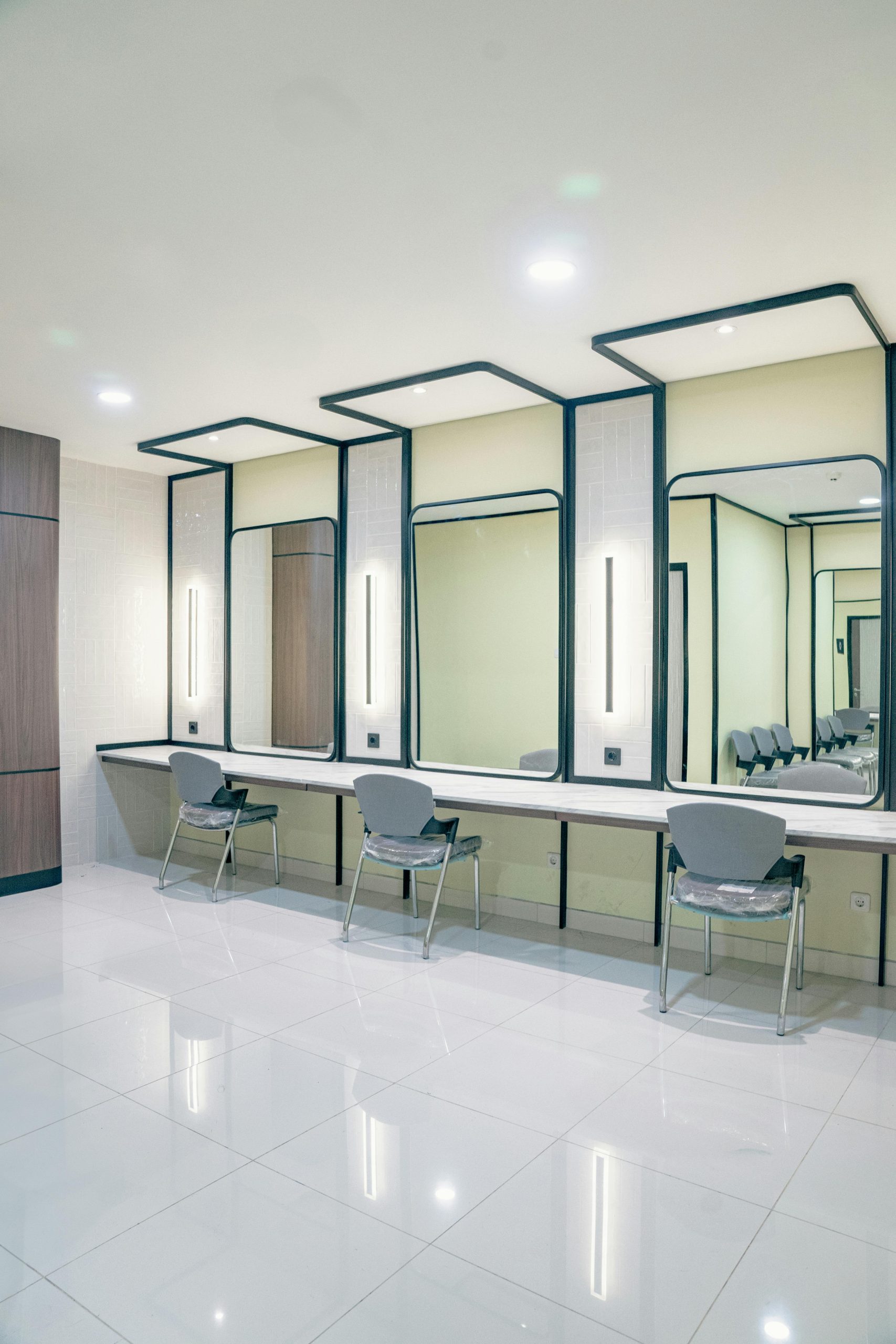 A sleek and modern makeup room featuring large vanity mirrors and chic seating.